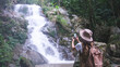 © Farknot Architect - Rear view image of a woman taking photo of the waterfall in the forest