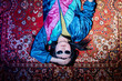 © Seventyfour - Portrait of young adult Asian woman lying on vintage patterned carpet wearing sunglasses, holding head with one hand, embodying retro style and second hand fashion concept