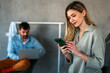 © NDABCREATIVITY - Smiling young female using mobile phone app playing game, shopping online, ordering delivery