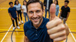 © Alex - Male teacher giving thumbs up in gym symbolizing leadership