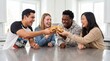 © Таня Андреева - Happy diverse group of young friends laughing and toasting with burgers while enjoying fast food together in a modern kitchen.