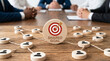 © Kaluya Stock - Business meeting concept with a wooden target block labeled 'SHARED GOAL' on a conference table, illustrating collaboration and strategy
