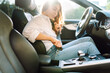 © maxbelchenko - A young woman behind the wheel fastens her seatbelt. A female driver observes safety precautions and fastens her seatbelt while sitting in a car. Concept of transportation and leisure.