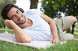 © auremar - handsome man wearing headphones lies on the grass