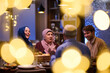 © .shock - Muslim family shares iftar meal in restaurant during Ramadan with decorations and warm atmosphere