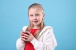 © New Africa - Little girl with glass of pomegranate juice on light blue background