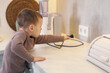 © New Africa - Child safety at home. Little boy plugging electric juicer into power outlet in kitchen