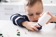 © New Africa - Child safety at home. Little boy playing with pills at table in kitchen, closeup