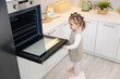 © New Africa - Child safety at home. Little girl opening oven in kitchen