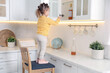 © New Africa - Child safety at home. Little girl on chair opening cabinet with alcohol in kitchen