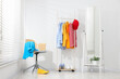 © New Africa - Different clothes hanging on rack, shoes, mirror and chair near white wall indoors
