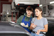 © JackF - Girl who owns car talks about problems to an auto mechanic at a car service center