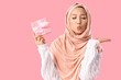 © Pixel-Shot - Beautiful Muslim woman with Christmas gift box blowing kiss on pink background