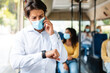 © Prostock-studio - Hurry up. Portrait of responsible man in medical mask having important call speaking by smart phone looking at his wrist watch on hand, going to work by bus. Punctuality, Communication Concept