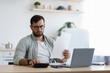 © Prostock-studio - Serious busy sad adult european guy with beard in glasses counts taxes on calculator with laptop, manages finances in bank accounts in kitchen interior. Bill payment, home bookkeeping, mortgage indoor