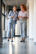 © Zoran Jesic - Professional businesswomen walking and discussing work in modern office hallway