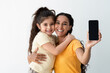 © Prostock-studio - Cheerful Arab Mother And Little Daughter Demonstrating Smartphone With Black Blank Screen At Camera, Happy Middle Eastern Mom And Child Embracing And Recommending New Mobile App, Copy Space, Mockup