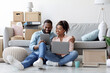 © Prostock-studio - Cheerful young african american lady and guy relaxing on couch using tablet for buying furniture online in room with cardboard boxes. Interior design planning, renovation, searching idea for new flat