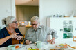 © Davor - Senior couple using smartphone at home kitchen table