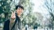 © miko - 公園でピースサインを出す笑顔の日本人男子大学生