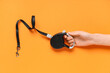 © Pixel-Shot - Female hand with black retractable dog leash and lead on orange background