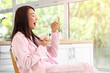 © Pixel-Shot - Pretty young Asian woman in pajamas eating tasty yogurt at home