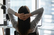 © fizkes - Office relax moment. Back view young woman corporate worker student take break for serene rest by laptop sit on chair in comfortable pose with fingers clasped behind head unwind distracted from screen