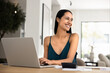 © fizkes - Cheerful young New Zealander woman working at computer from home, typing on laptop, doing domestic accounting work, analyzing financial data at workplace, looking away, smiling