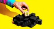 © lianlian liang - Hand choosing wooden block with lightbulb icon from pile of black bricks. Concept for creative idea, innovation, solution, standing out, unique thinking, and business wisdom. Yellow background.