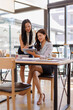 © David - Two busy business professionals women and woman business leaders partners checking document reading financial report talking working together on laptop computer in office at corporate meeting.