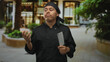 © Krakenimages.com - Man chef in black uniform holds cleaver with both hands in front in outdoor street plaza near building storefront and plants; pride craftsmanship.