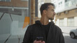 © Krakenimages.com - Young hispanic man using smartphone on a city street outdoors with a thoughtful expression in casual attire during daylight.