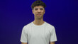 © Krakenimages.com - Young hispanic man squints eyes and scrunches nose in blue studio setting showing discomfort; disgust.