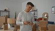 © Krakenimages.com - Young man in striped sweater smiling and counting dollar bills in living room surrounded by moving boxes, reflecting new home excitement and transition.