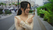 © Krakenimages.com - Young chinese woman smiling and pointing on a busy street outdoors with buildings and greenery in the background, suggesting directions or a choice to make.