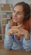 © Krakenimages.com - Woman with headset speaking and hands clasped at desk in a warehouse office, engaging in customer support and conversation; friendly support.