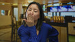 © Krakenimages.com - Woman sending kiss in indoor restaurant with vibrant lighting, exuding confidence and charm in her blue outfit