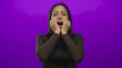 © Krakenimages.com - Woman expressing surprise in front of a vibrant purple wall, her hands framing her face, highlighting a sense of astonishment and the contrast with the solid color background.