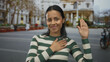© Krakenimages.com - Woman making oath gesture on street in vibrant city scene, showcasing determination and confidence in an urban outdoor environment.