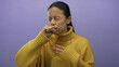 © Krakenimages.com - Woman in yellow sweater coughing against a plain purple wall, displaying discomfort and illness, representing health and wellness issues.