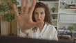© Krakenimages.com - Woman holds palm forward stop gesture at computer screen with focused posture while seated in building; determination assertion.