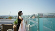 © Krakenimages.com - Woman leaning on glass rail with bare forearm resting on cruise ship deck railing, smiling toward sea and distant shore; serenity travel.