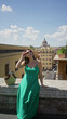 © Krakenimages.com - Woman sitting on a stone wall on a rome street in a green dress and sunglasses, looking up toward a domed building; serenity travel wanderlust.