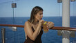 © Krakenimages.com - Woman sipping an iced cocktail with straw at cruise ship deck rail, leaning on wooden rail with lemon garnish and glass visible; relaxation.