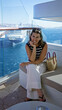 © Krakenimages.com - Woman shading forehead with hand beside woven straw bag on a ship terrace with glass railing and distant cruise building visible; serenity relaxation.