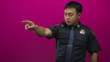 © Krakenimages.com - Policeman in navy uniform points index finger forward in magenta studio with badge visible; authority.