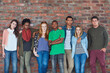 © peopleimages.com - Portrait, college students and group on brick wall for fashion, gen z style and bonding together. Team, friends and cool people at university for diversity, attitude and arms crossed with streetwear