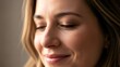 © Tur - Close Up Portrait of a Smiling Woman with Brown Wavy Hair in Soft Natural Lighting Against a Neutral Background Revealing Textured Skin and Delicate Features