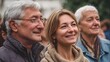 © Bussakon - A man and two women appearing happy and engaged observe something together outdoors in a crowd bathed in natural light
