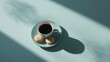 © MdSaifullaharman - Overhead shot of a cup of coffee with two macarons on a blue surface in sunlight